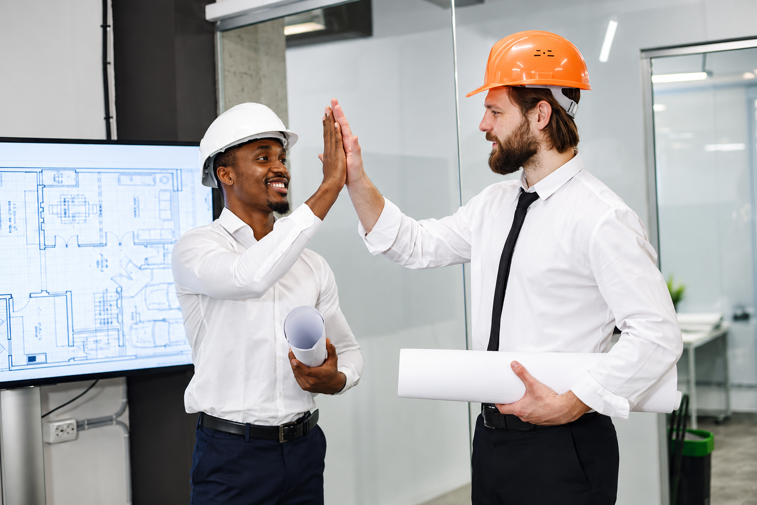 Two engineers celebrating a successful project review over technical drawings